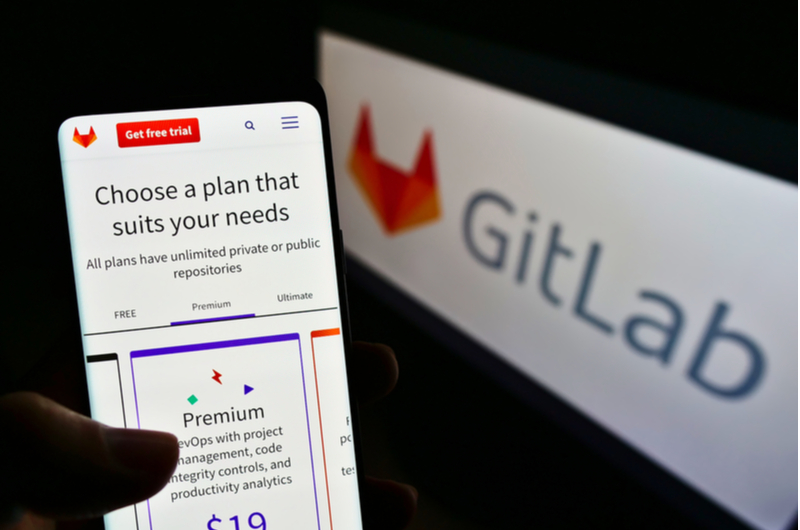 A person holding a mobile phone with the logo of the American DevOps software platform "GitLab"